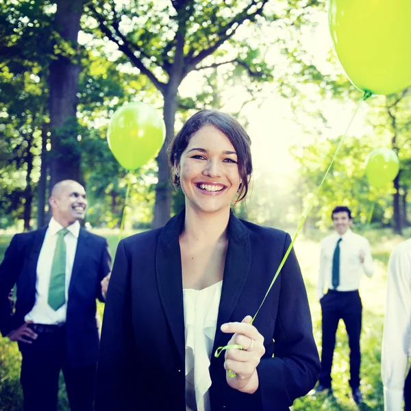 People outdoors holding green balloons