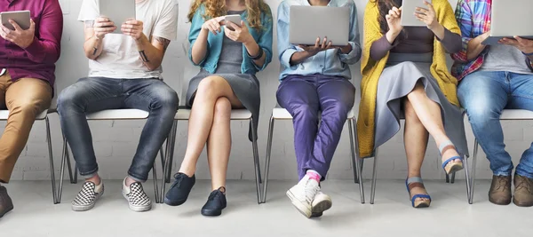 People with devices sitting on chairs