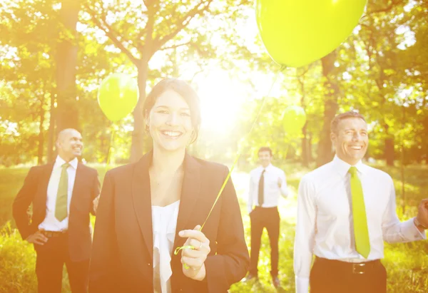 People outdoors holding green balloons