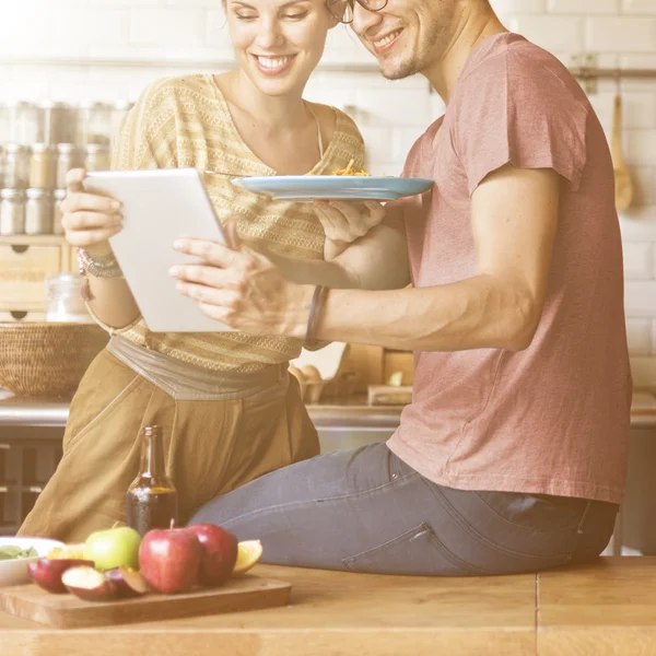 couple in kitchen with  digital device
