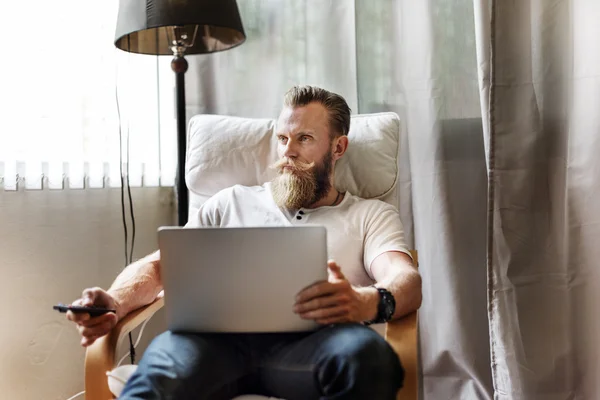 Man Sitting in Armchair and Using Laptop