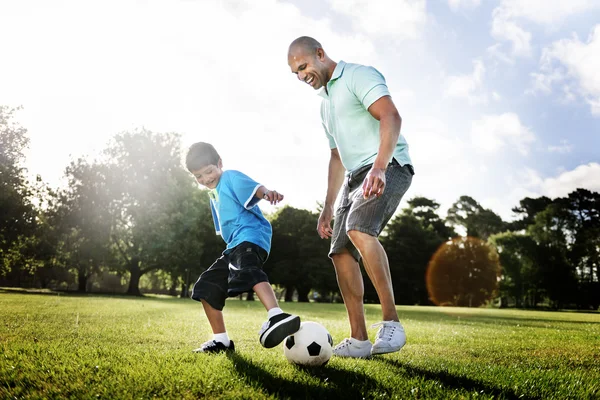 Father playing football with little son