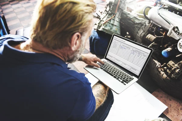 Car mechanic with laptop in Garage