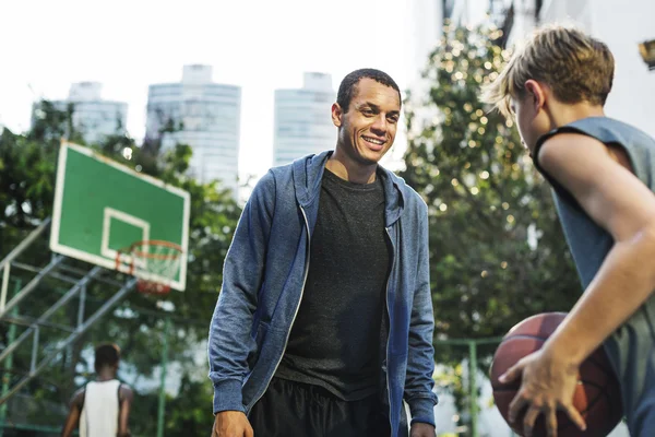 Sportsman teaching boy play Basketball