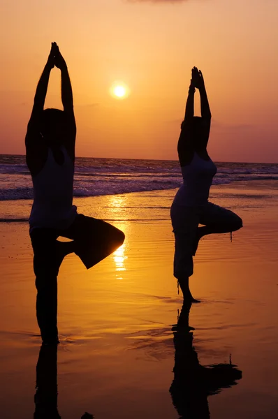 People in beach doing yoga