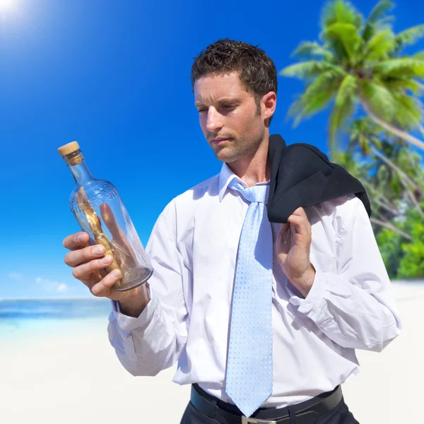 Businessman looks at message in bottle