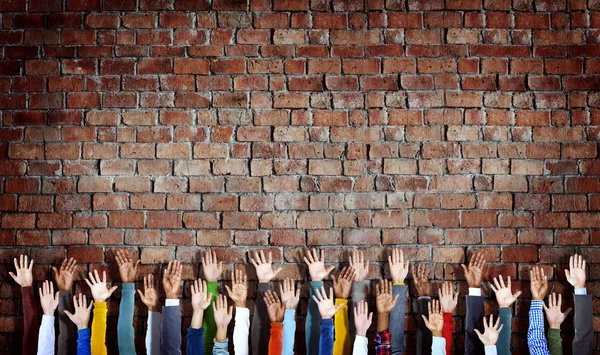 Diverse Hands Raised on Brick Wall
