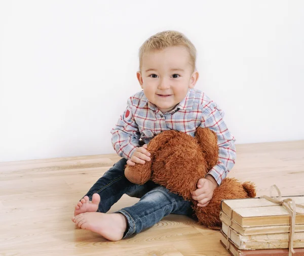 Studio shot of little cute smiling boy with his toy and books