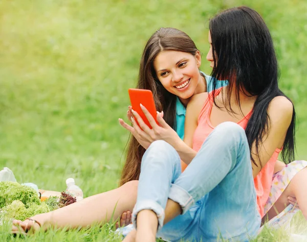 Two women friends laughing and sharing pictures in a smart phone