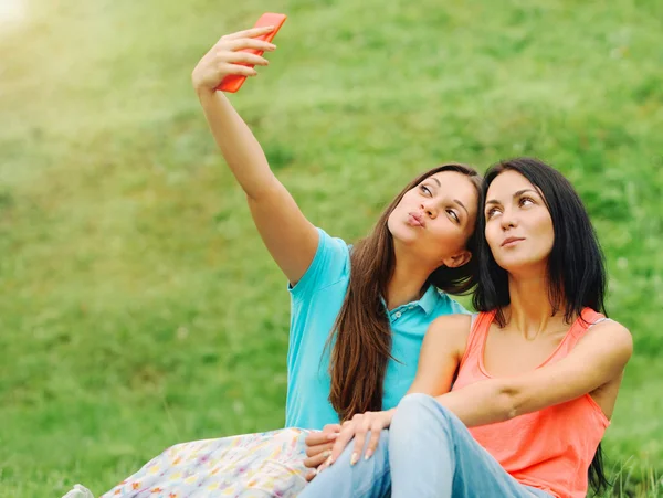 Two women friends taking pictures of themselves with phone on pi