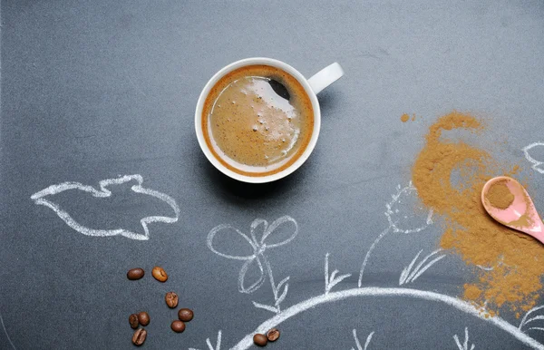 Mug of coffee with happy drawing and cinnamon on the blackboard