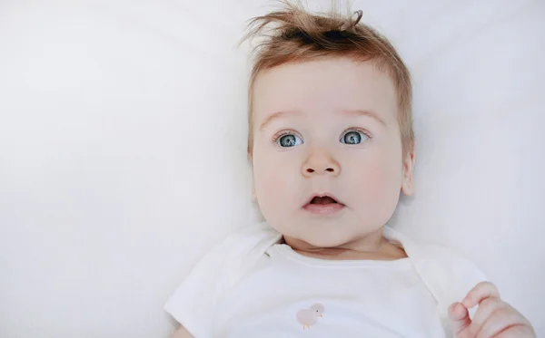 Portrait of cute little baby boy lying on soft white pillow