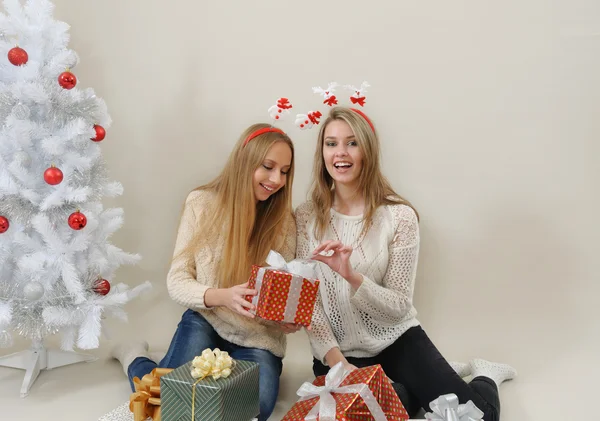 Two happy women with gift boxes open one of them