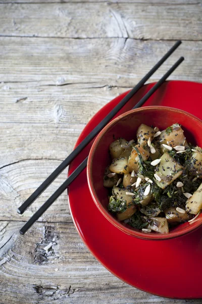 Roasted japanese turnips with leaves and seeds on red bowl with chopstick on rustic background