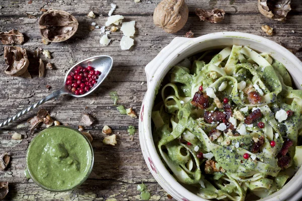Italian handmade pasta with pesto basil green sauce with pink peppercorn and walnuts on bowl