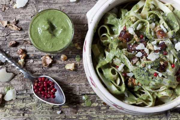 Italian handmade pasta with pesto basil green sauce with pink peppercorn and walnuts on bowl