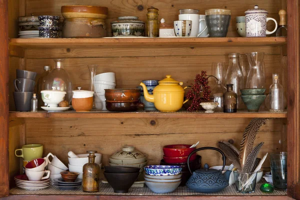 Ceramics and kitchen equipment on rustic and country style wooden shelves
