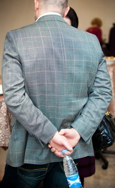 Man stands with his back to the viewer and holding a bottle of water