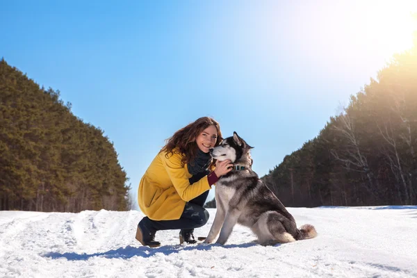 Woman plays with dog in the winter forest