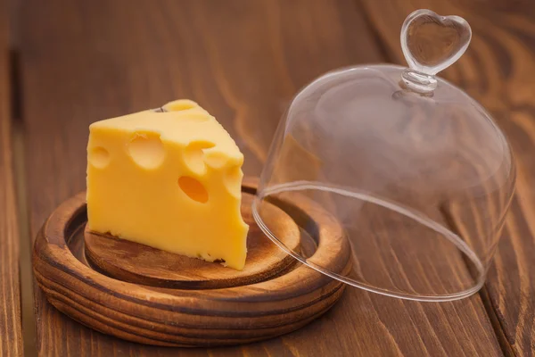 Opened glass  dome with piece of cheese