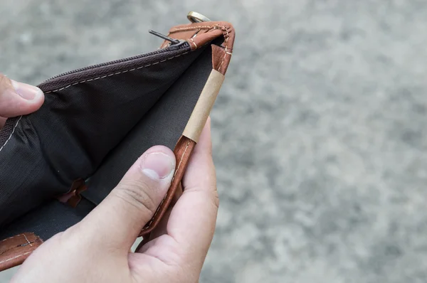 Broke man showing his brown leather wallet with no money