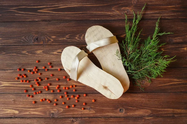 Hand-made wooden slippers with red mountain ash or rowan berries on rustic wooden background