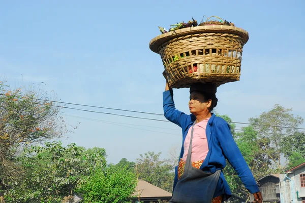 Myanmar woman  carrying  basket on her head.