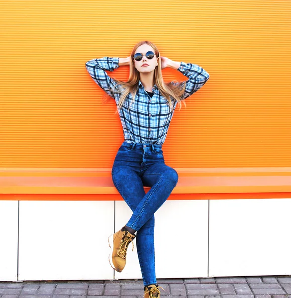 Fashion pretty blonde girl posing over colorful orange backgroun