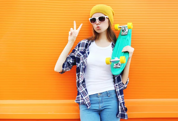 Fashion cool girl with skateboard having fun over colorful orang