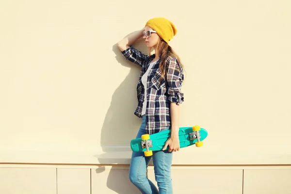 Fashion pretty girl wearing a colorful clothes with skateboard o