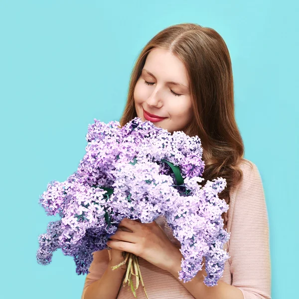 Cute woman enjoying smell of bouquet lilac flowers over colorful