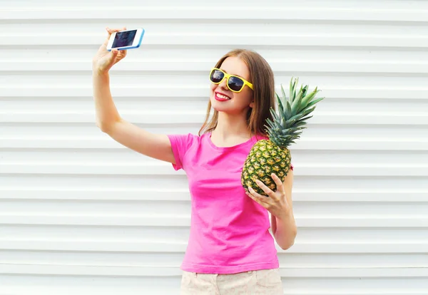 Pretty girl in sunglasses with pineapple taking picture selfie o