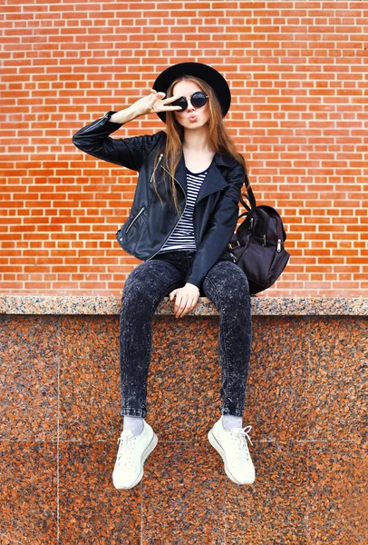 Fashion pretty cool woman in black rock style over bricks backgr