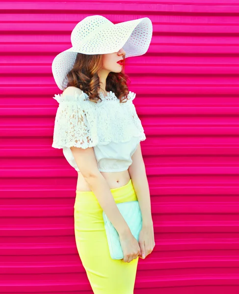 Fashion woman in summer straw hat with handbag clutch over color