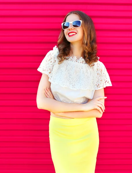 Happy pretty smiling woman in sunglasses and skirt over colorful