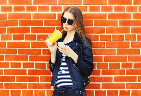 Fashion pretty young woman in black rock style drinks juice from