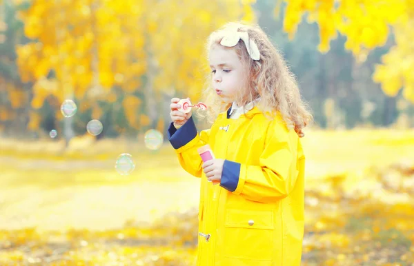 Happy little girl child playing blowing soap bubbles in sunny au
