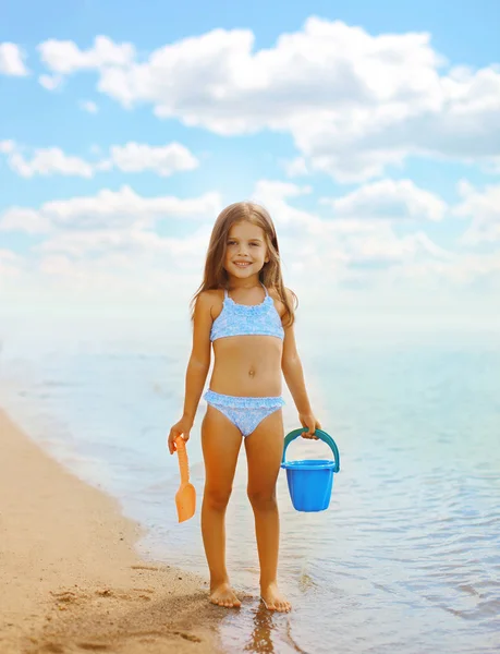 Happy little girl playing on the beach near sea, summer, vacatio