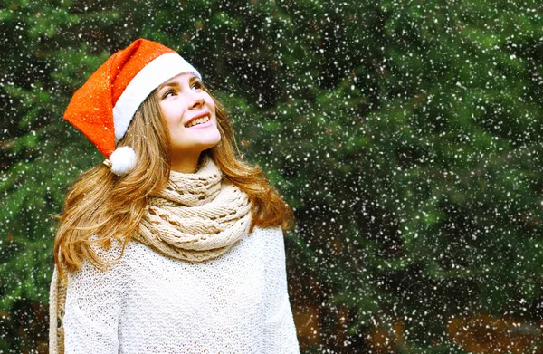 Christmas and people concept - happy girl in winter hat near tre