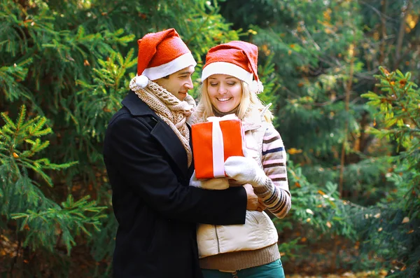 Christmas and people concept - man giving a box gift to a woman,