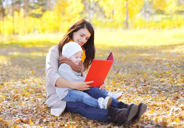 Mother and child looking on book or tablet pc sits together on l