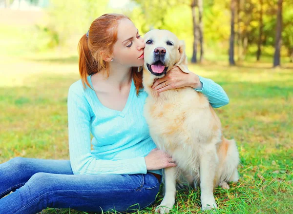 Happy owner woman and Golden Retriever dog on grass