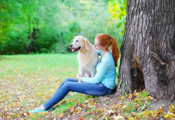 Happy owner woman and Golden Retriever dog together sitting near