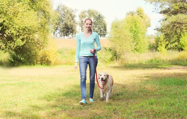 Happy owner woman and Golden Retriever dog walking together in s
