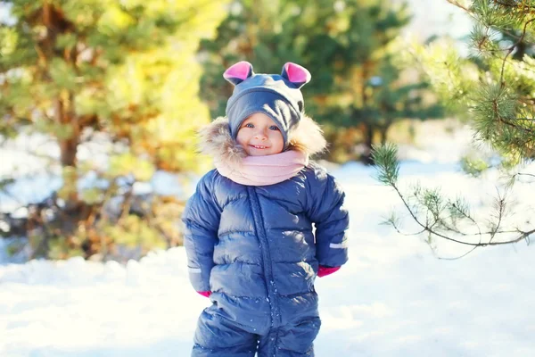 Cute smiling little child on snow walking in sunny winter day