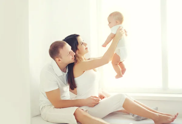 Happy family, mother and father playing with baby home in white
