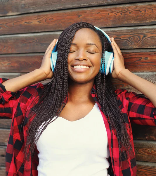 Beautiful smiling african woman with headphones enjoying listens