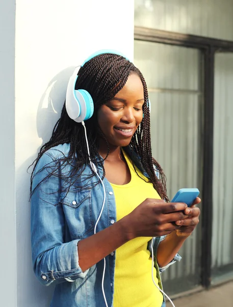 Beautiful smiling african woman with headphones listens to music