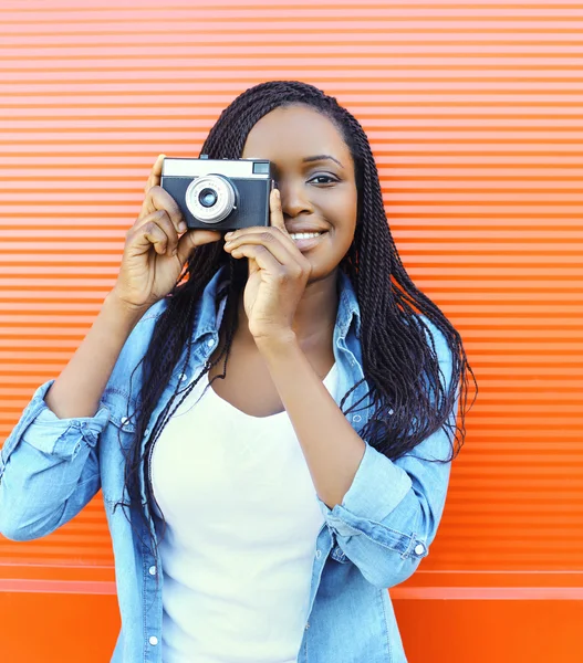 Portrait happy smiling african woman with old vintage camera ove