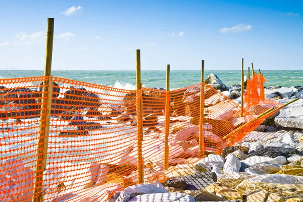 Construction site with safety orange grid at the seaside